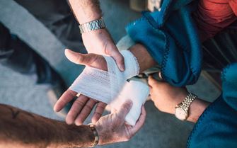 A person applying a bandage to a casualty's hand.