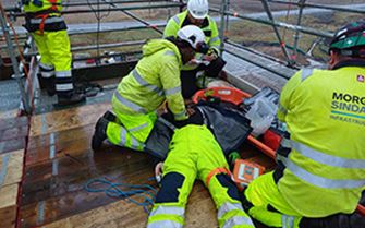 A construction worker performing CPR on his colleague.