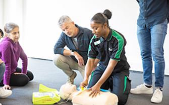 A St John Ambulance trainer demonstrating first aid skills to a group of learners.
