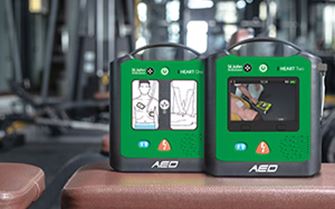 The St John Ambulance HEART One and HEART Two defibrillators on a table inside of a gym.
