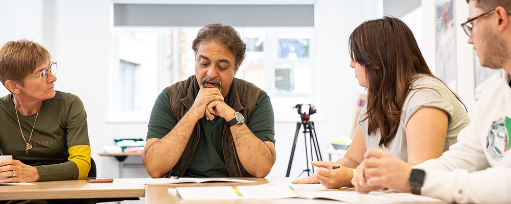 A group of people sitting around a table, having a discussion.
