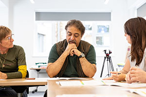 A group of people sitting around a table, having a discussion.