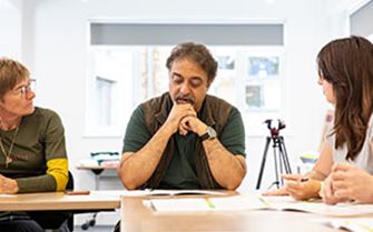 A group of people sitting around a table, having a discussion.