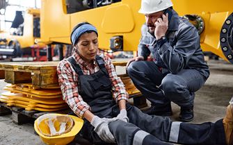A woman sitting on the ground with an injured leg.