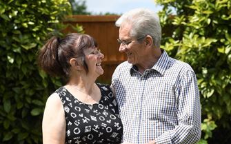 Gwen and John looking at each other standing in a garden.