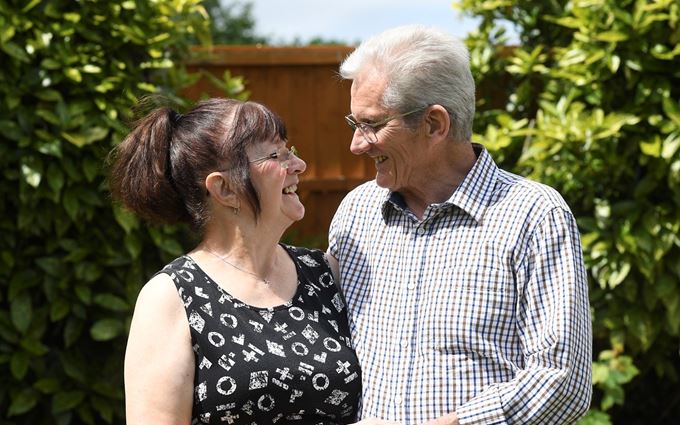 Gwen and John looking at each other standing in a garden.