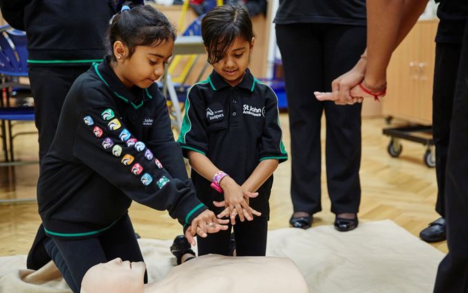 Two young Badger girls practising CPR on a  mannequin.
