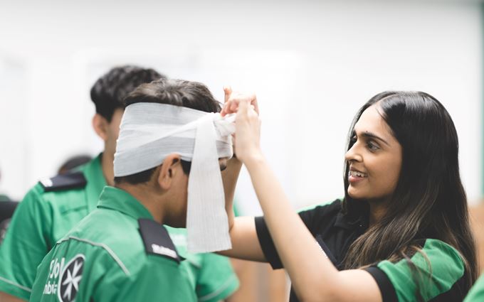 Youth team volunteer bandaging a Cadet's head