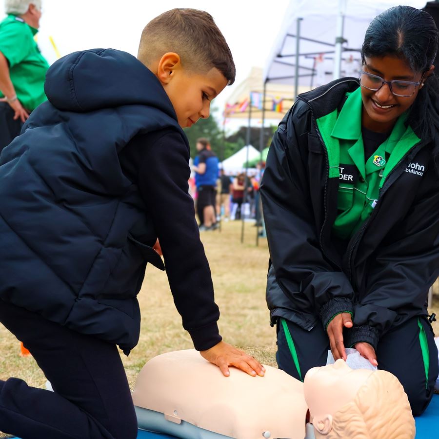 Cadet First Aider showing a young teenager how to do CPR.