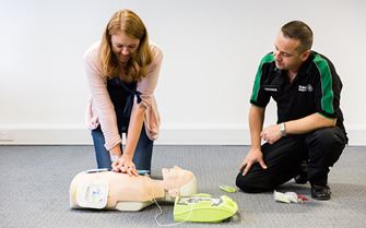 Woman practicing CPR using a training mannequin