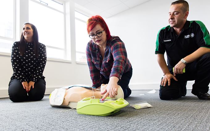 Woman learning to use a defibrillator