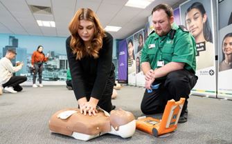St John Ambulance volunteer teaching a woman CPR