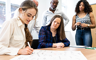 People gathered around a desk, writing down ideas.