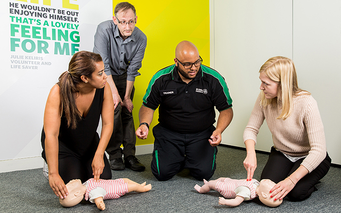 First aid course participants practicing baby CPR on a training mannequin.