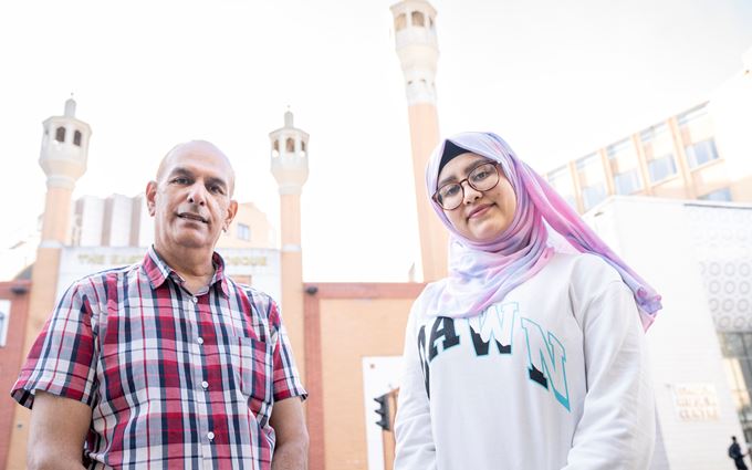 A man and young woman standing in front of a tall building.